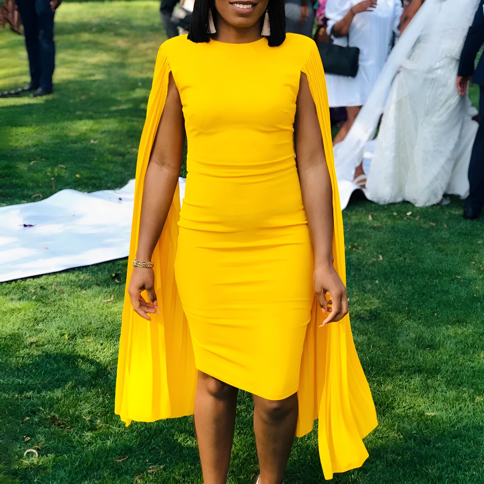 Yellow long sleeve evening gown with high waist and pleated skirt, model facing forward.