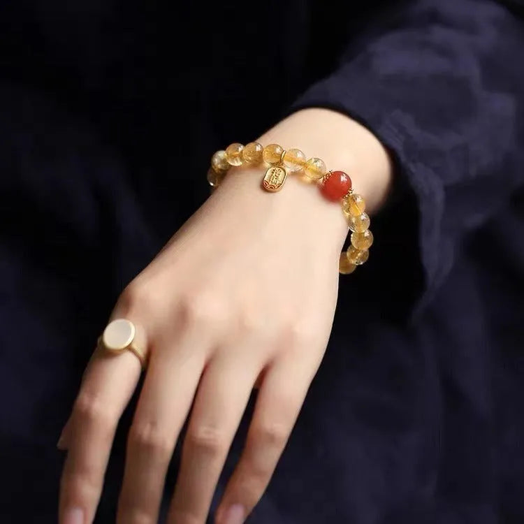 Natural red agate bead bracelet with gold-coloured spacers on a wrist.