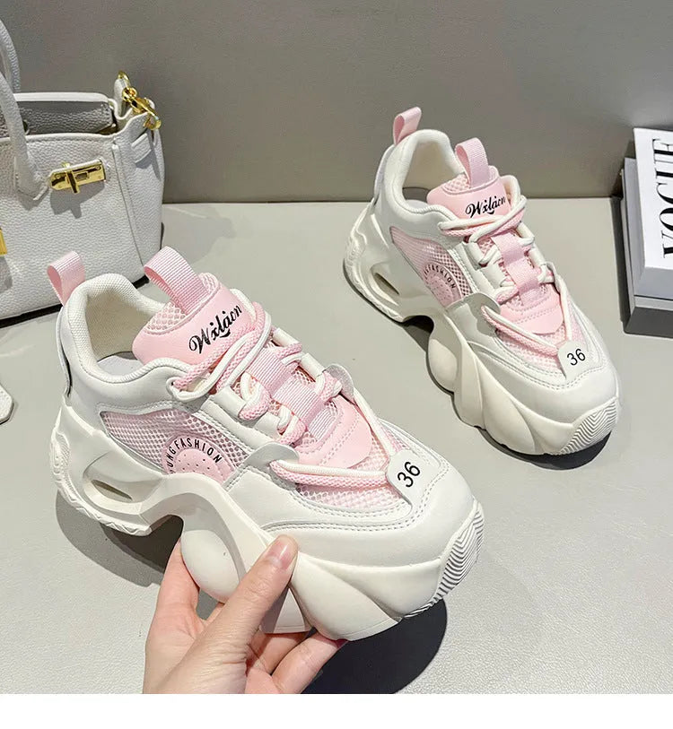 Women's pink casual sneakers with a thick sole, cross-strap detail, and lace-up closure on a white background.