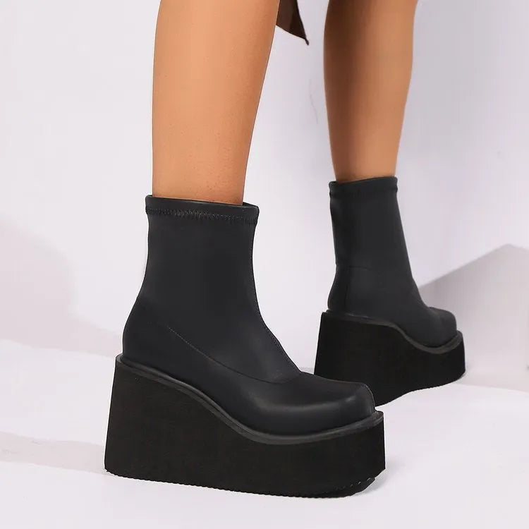 Women's black wedge-heel ankle boot with a round toe and waterproof platform sole on a plain background.