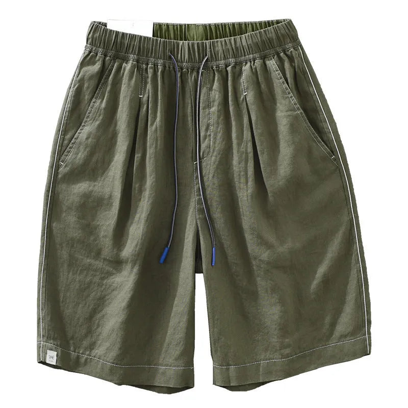 Man wearing loose straight-leg linen shorts in green, showcasing mid-waist and drawstring detail.