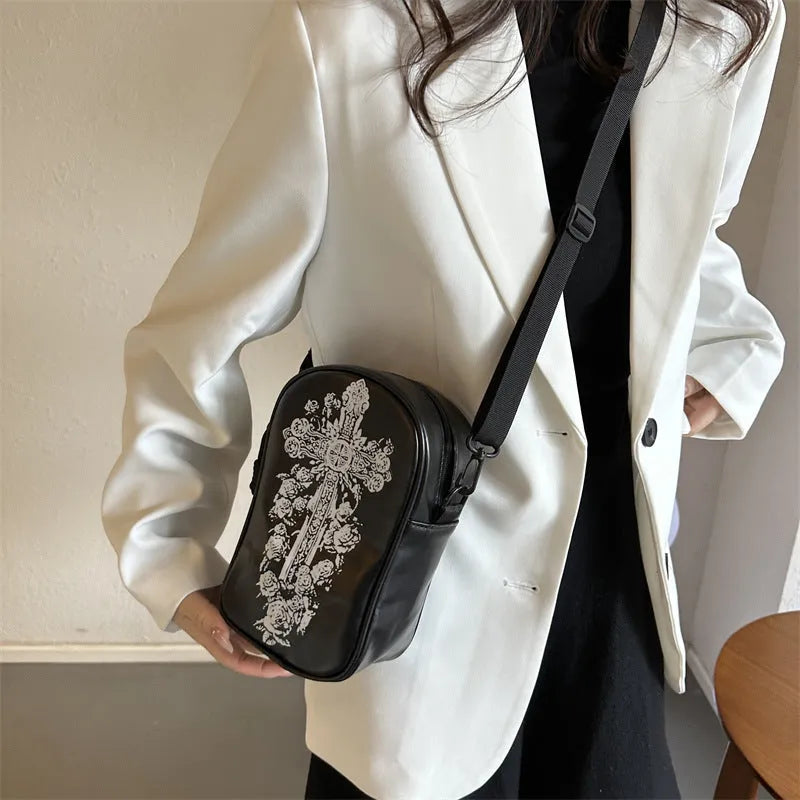 Black Halloween crossbody bag with orange pumpkin, white ghost, and bat graffiti print, shown worn across the body.