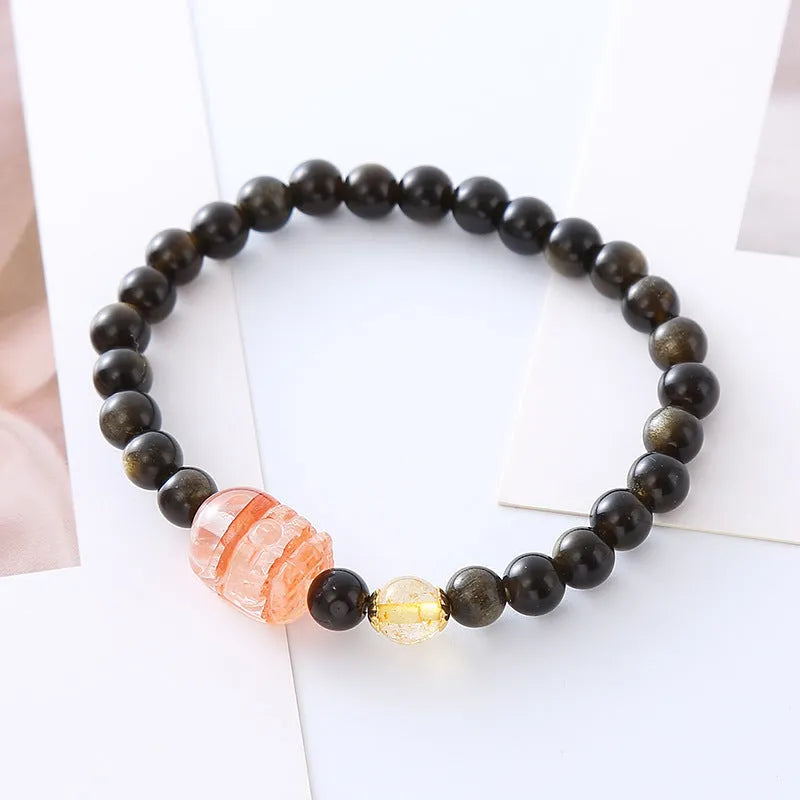 Handmade black obsidian and gold Pi Xiu charm bracelet with red flowers.
