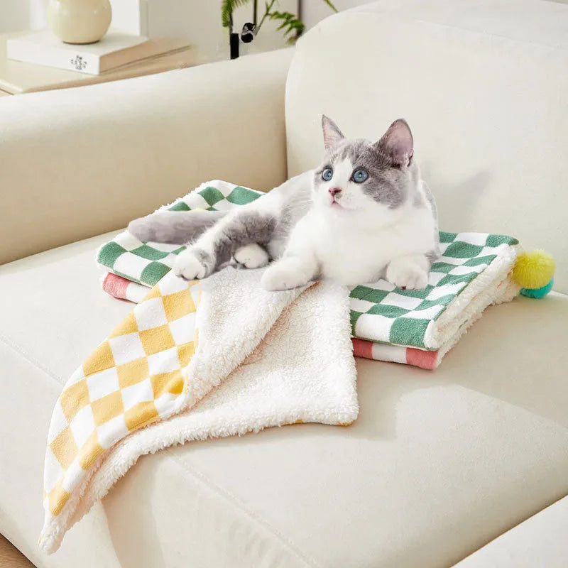 Plush pet blanket with plaid pattern and fur ball decoration for cats and dogs on sofa
