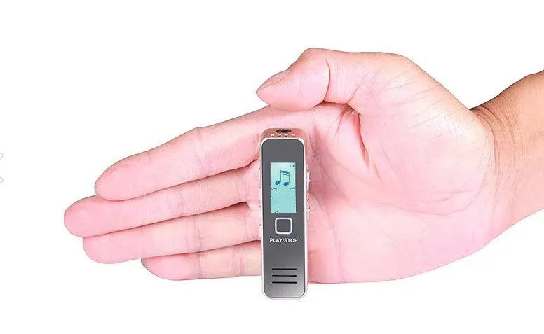 Small black or gold portable digital voice recorder with USB cable on a desk.