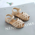 Child wearing white buckle toe soft sole woven sandals on a sunny day