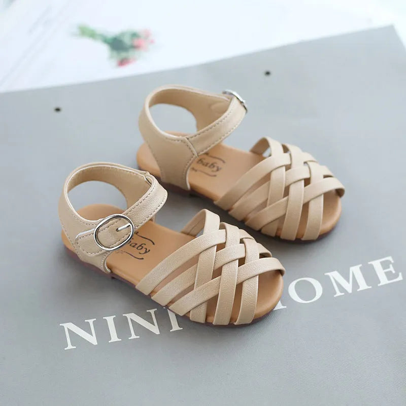 Child wearing white buckle toe soft sole woven sandals on a sunny day
