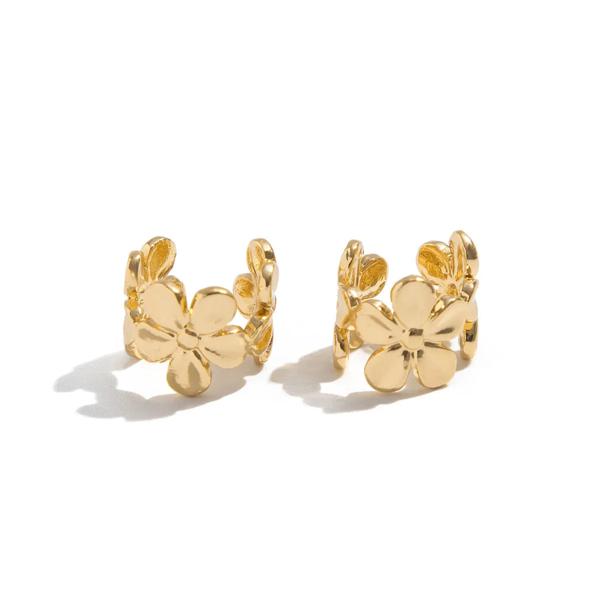 Gold coloured starfish and conch drop earrings on a white background.