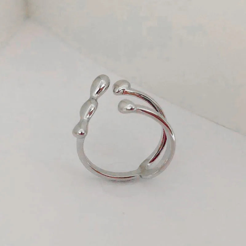 Gold brass opening ring with sphere design on a white background.