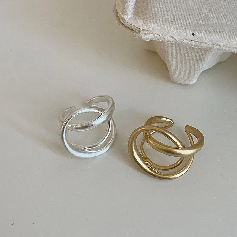 Geometric open ring with interlaced matte metal design in gold or silver plating.