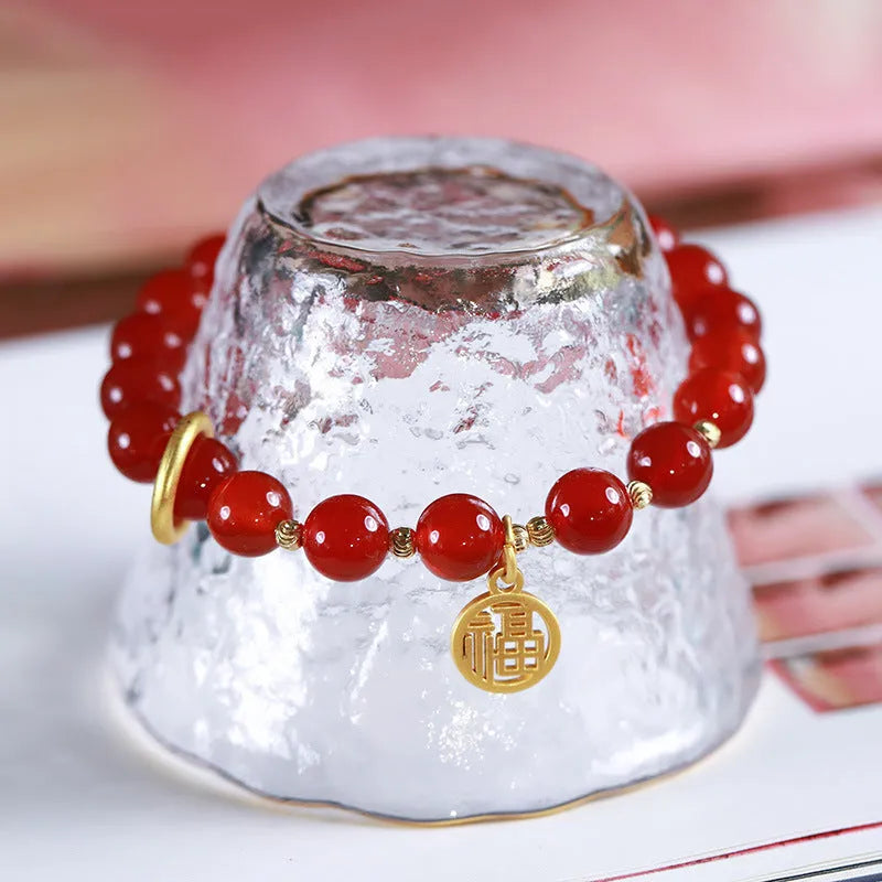 Close-up of a red agate beaded bracelet with woven design and a paper blessing card.