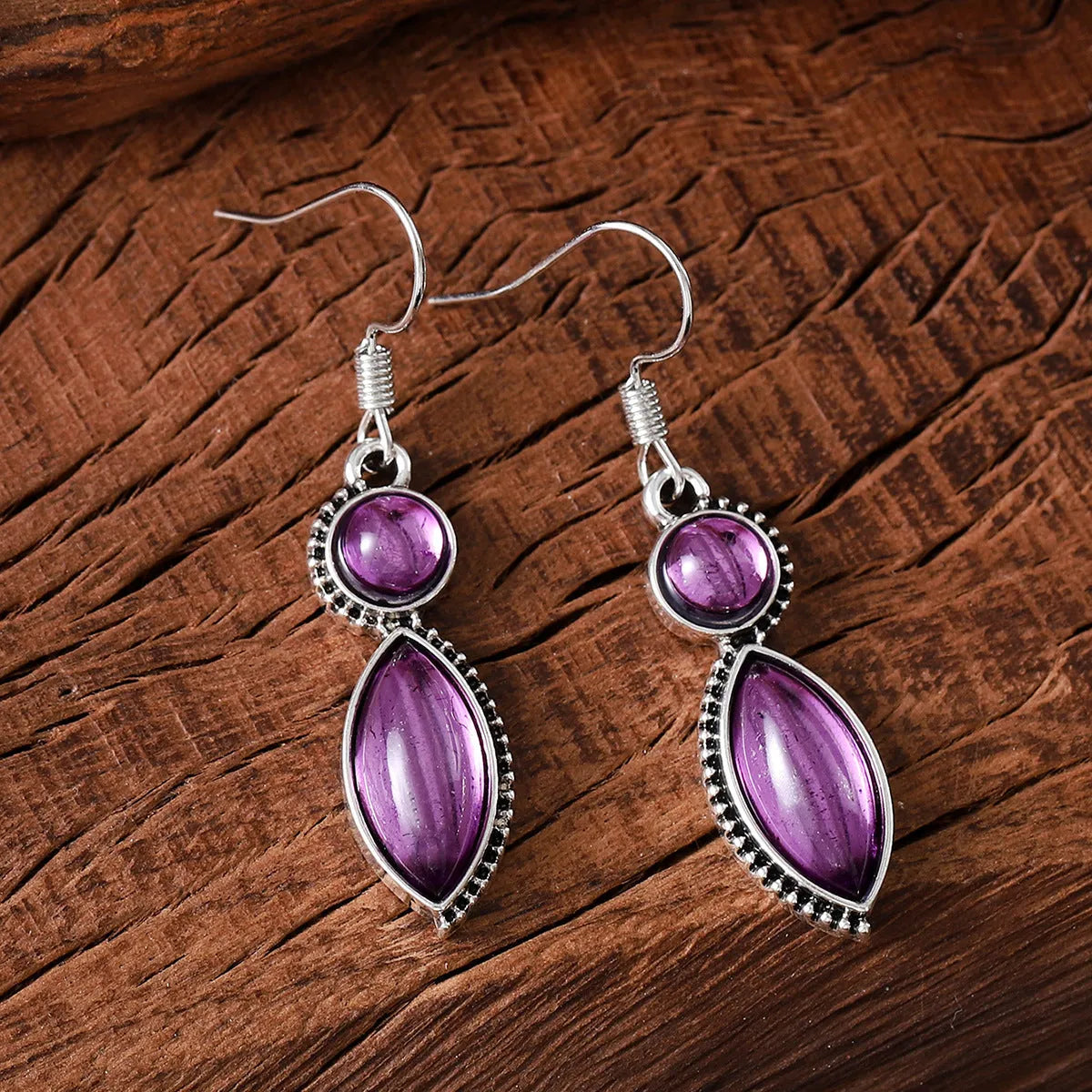 Vintage silver-tone geometric drop earrings with round purple and black stones on a grey background.