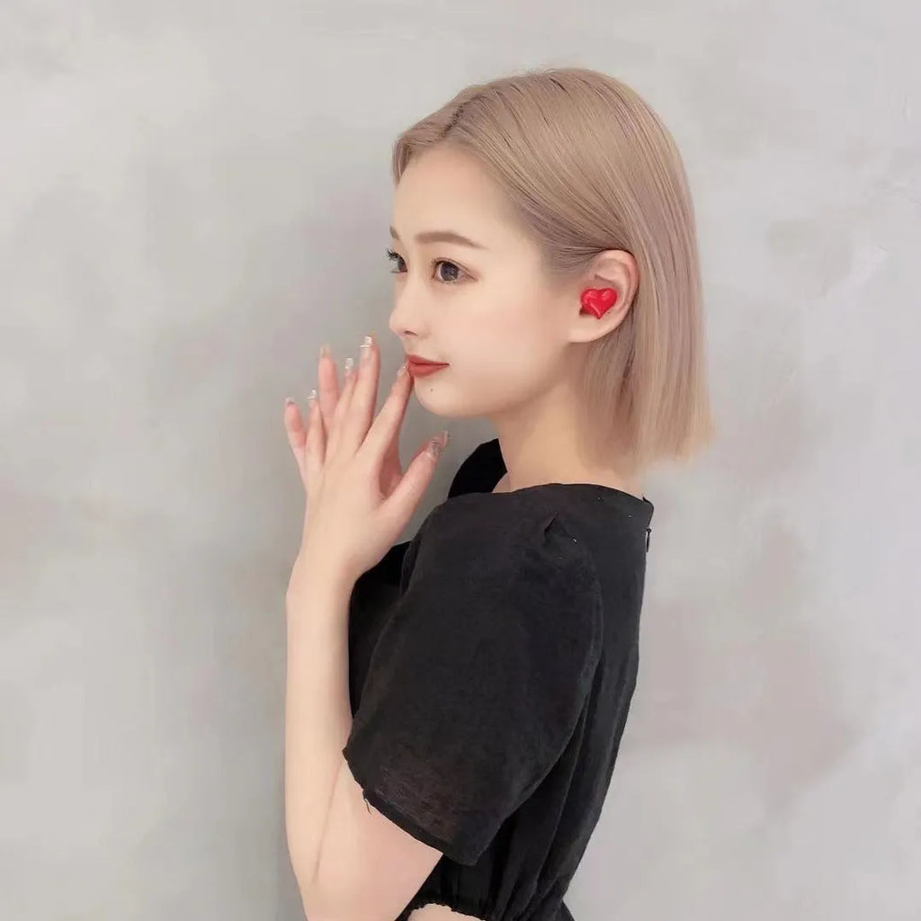 Heart-shaped wireless Bluetooth earbuds in red or pink colours with charging cable