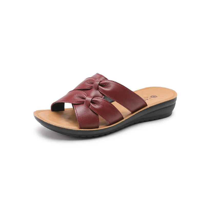 Women's beige cowhide slippers with a soft sole on a plain background.