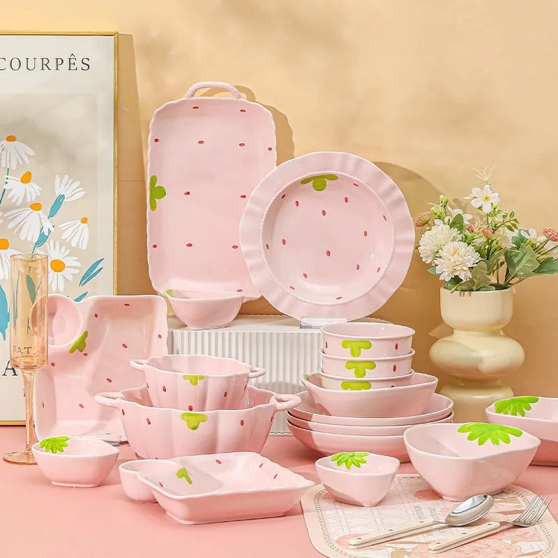 Porcelain dinnerware set with strawberry design showing bowls, plates, and a twist spoon.