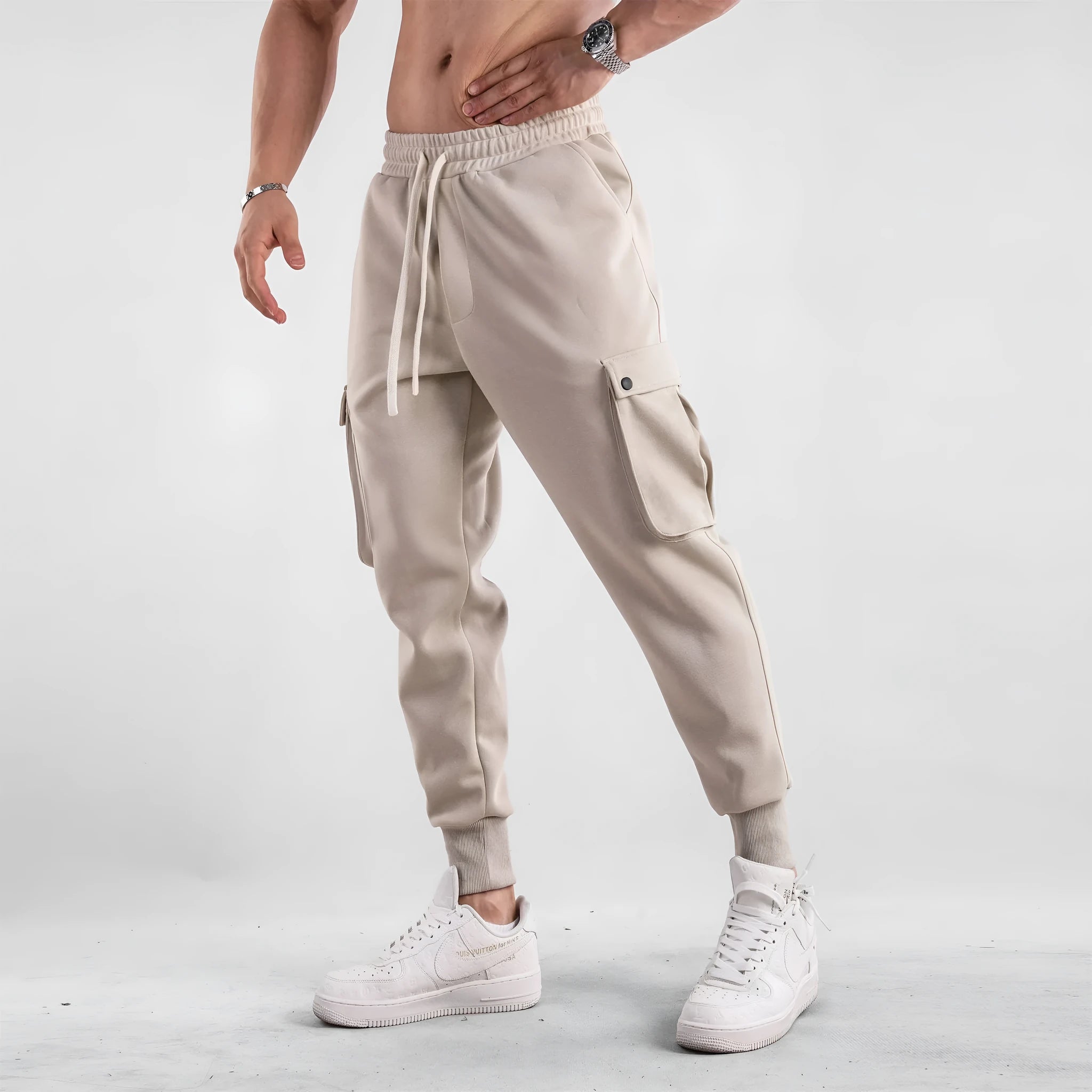 Men's loose-fit cotton sports trousers in apricot colour with ankle ties and multiple pockets, laid flat.