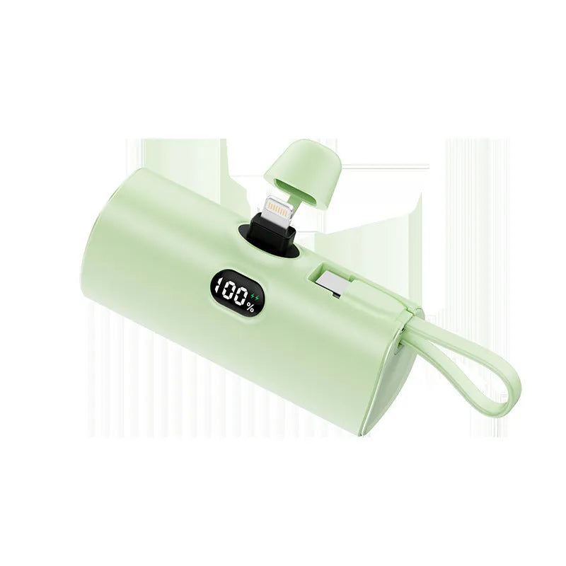 Compact capsule-shaped wireless power bank with digital display and integrated plug, shown in multiple colours.