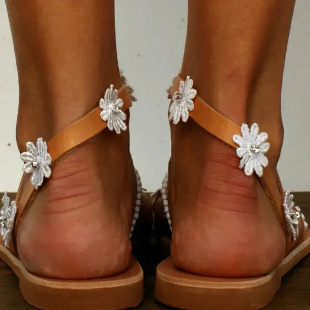 Brown ladies flat sandals with floral pattern, herringbone toe, and rubber sole.