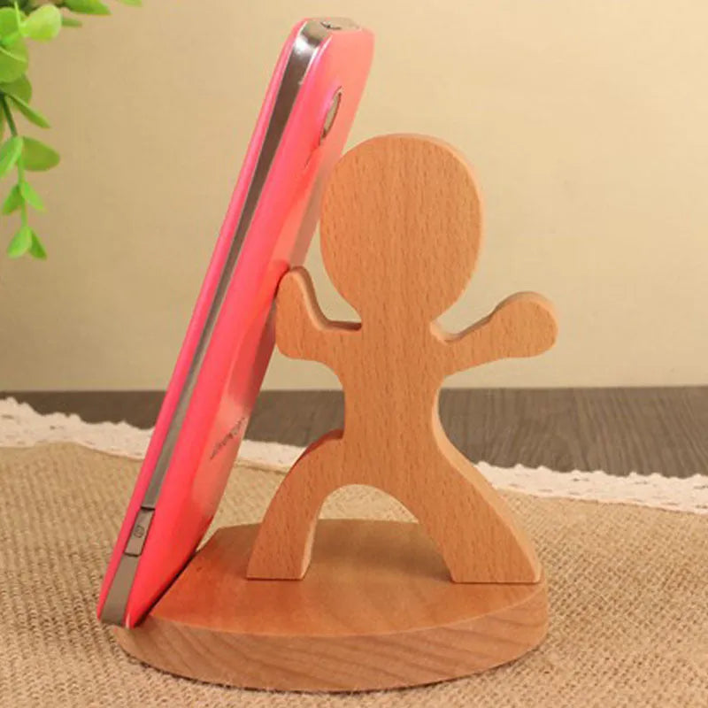 Solid beech wood mobile phone stand with a resin cow figurine and a slot for holding coins on a wooden desk.