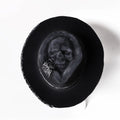 Handmade wool felt conical crown skull hat for Halloween costumes on a dark background.
