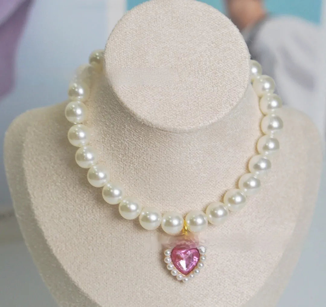 Pearl necklace cat collar with heart-shaped gem charm in various colours on a white background.