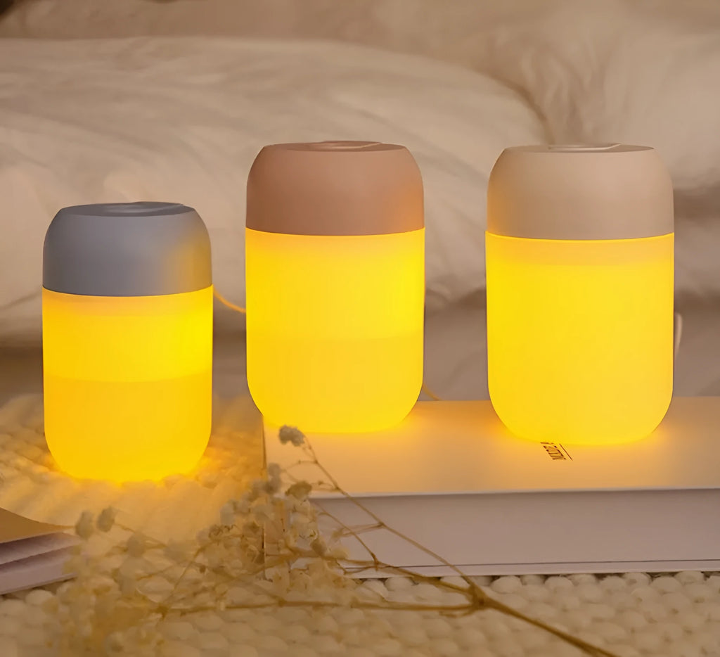 Small white cylindrical USB mini humidifier on a surface with its charging cable.