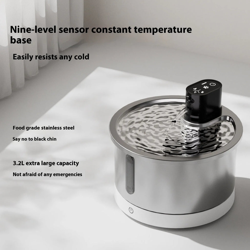 Stainless steel pet water fountain with a white constant temperature heating base on a wooden floor.