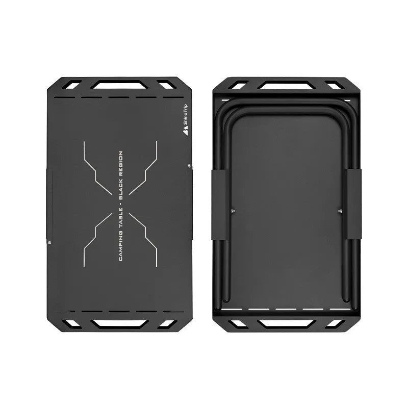 Black folding outdoor camping table with steel frame and storage bag on a campsite