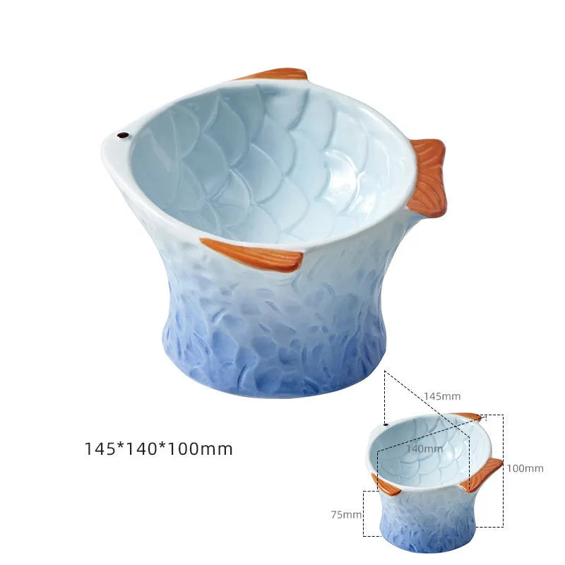 Blue ceramic fish-shaped cat bowl with tilted design and non-slip base on a wooden surface