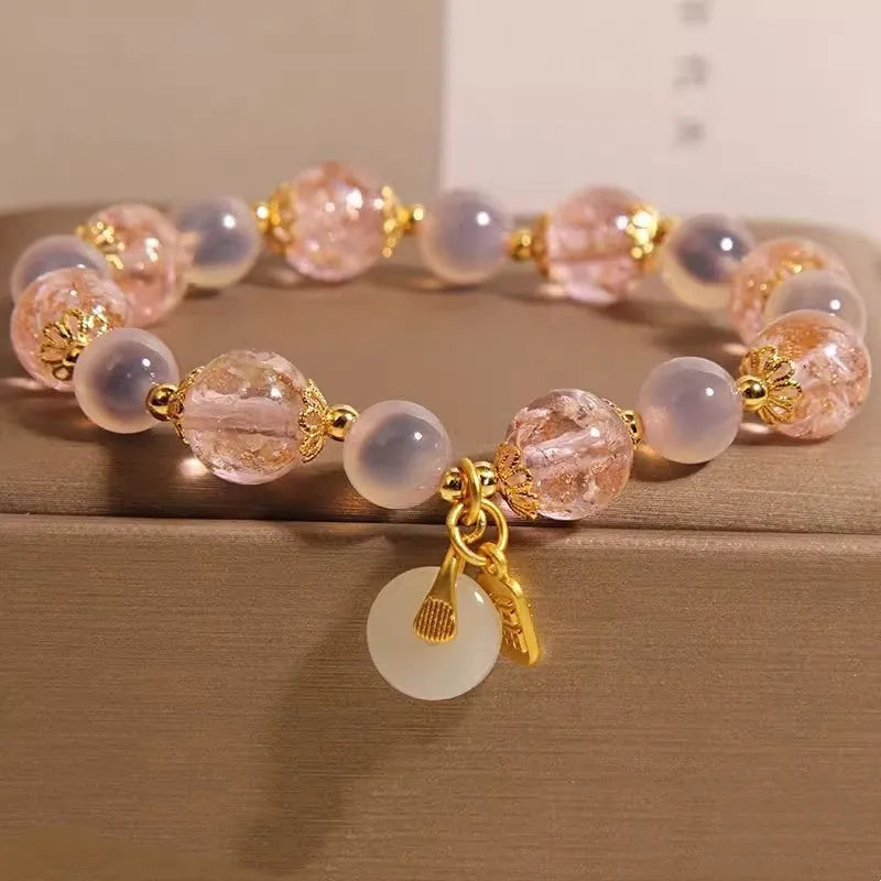 Close-up of a women's pink agate heart bracelet with a luminous glaze and a silver peace buckle clasp.