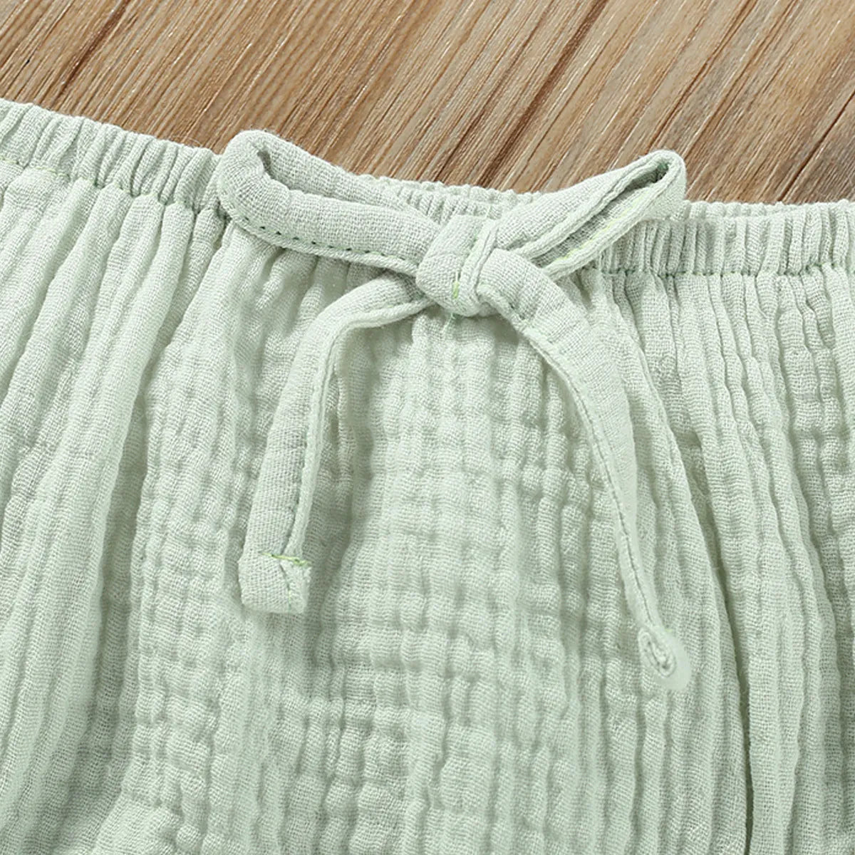 Green cotton girls' two-piece set with sleeveless sling top and matching short hot pants.
