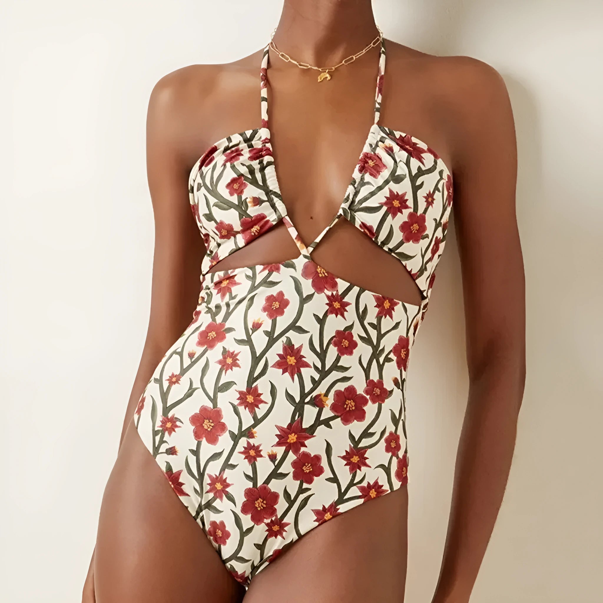 Female model wearing two-piece halter neck swimsuit with floral print and hollow-out gauze skirt cover-up