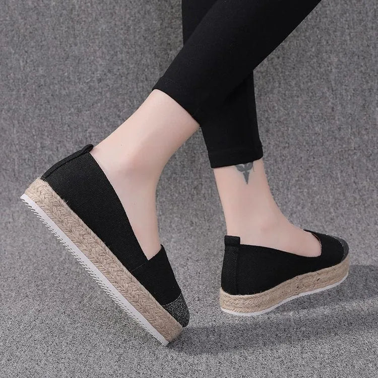 Plus size beige canvas slip-on flat shoes with a round toe on a white background.