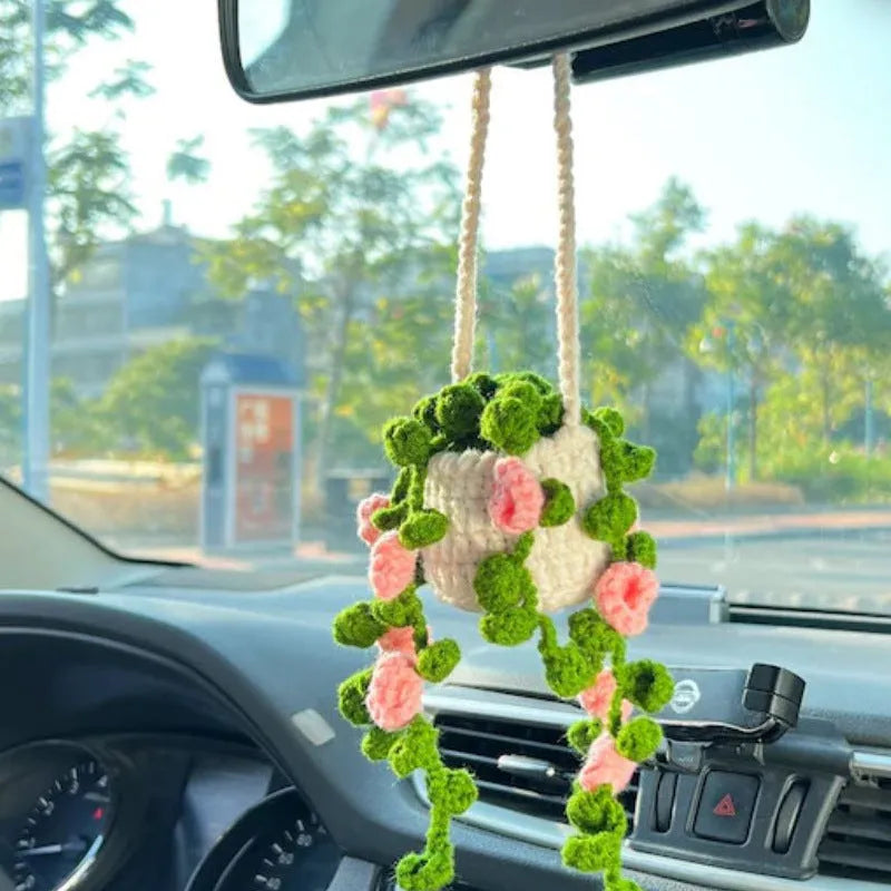 Green and white knitted wool car plant ornament hanging from a rope