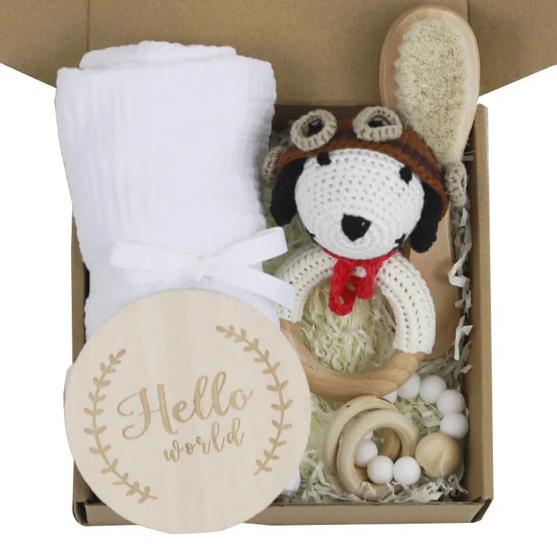 Baby teething toy gift set showing gauze blanket, wooden bell, gum teether, tire brush, and milestone on white background