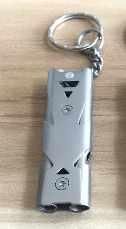 Compact metal keychain whistle with black lanyard on a keyring for outdoor emergency use