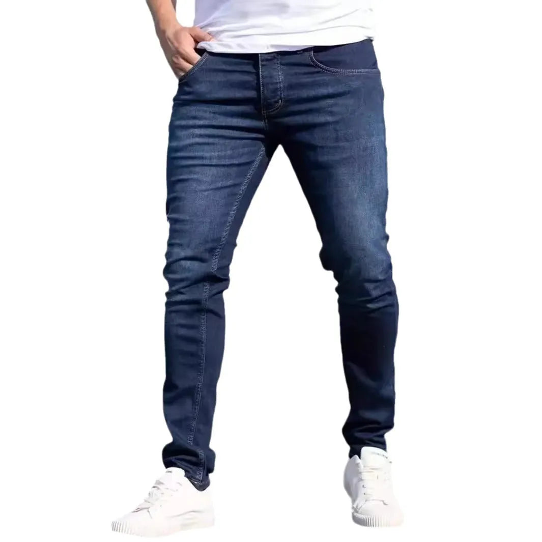 Man wearing dark blue slim-fit skinny jeans with a medium-elastic waist and zipper fly.
