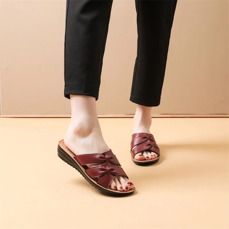 Women's beige cowhide slippers with a soft sole on a plain background.