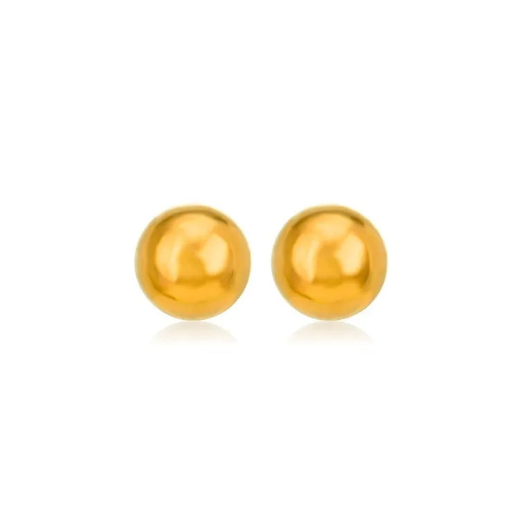 Close-up of minimalist round ball stud earrings in gold and silver finishes on a neutral background.
