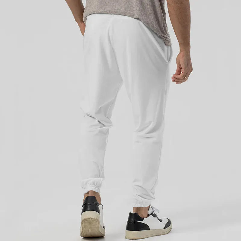 Man wearing grey loose tapered casual sweatpants with a straight leg and elasticated waistband.