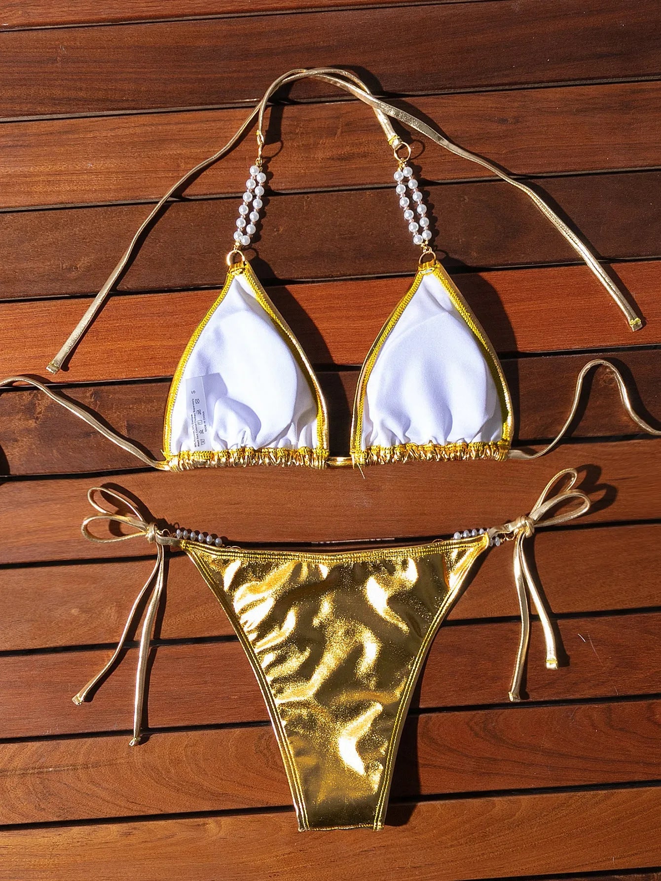 Gold halter neck bikini with lace-up front and pearl chain decoration
