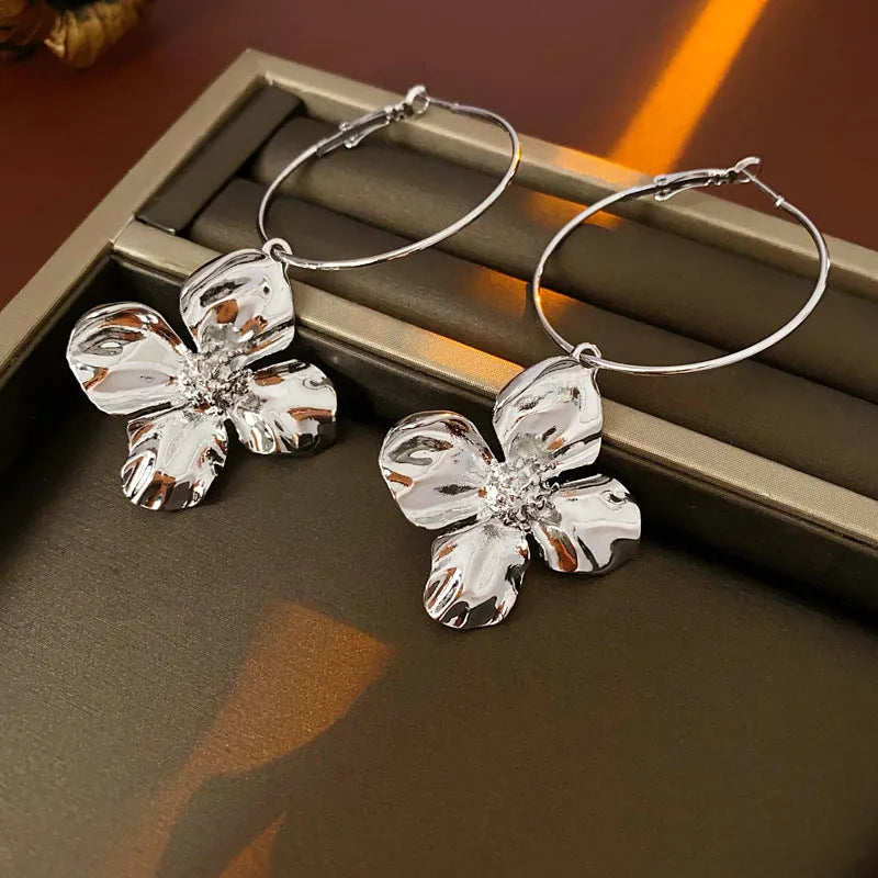 A pair of vintage-style floral drop earrings with geometric silver needle details, shown in a gold electroplated finish.