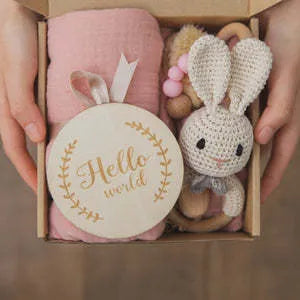 Baby teething toy gift set showing gauze blanket, wooden bell, gum teether, tire brush, and milestone on white background