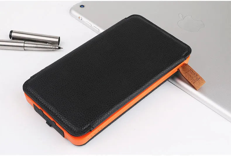 Black outdoor solar power bank with leather finish, showing solar panel and USB ports, next to a charging cable.