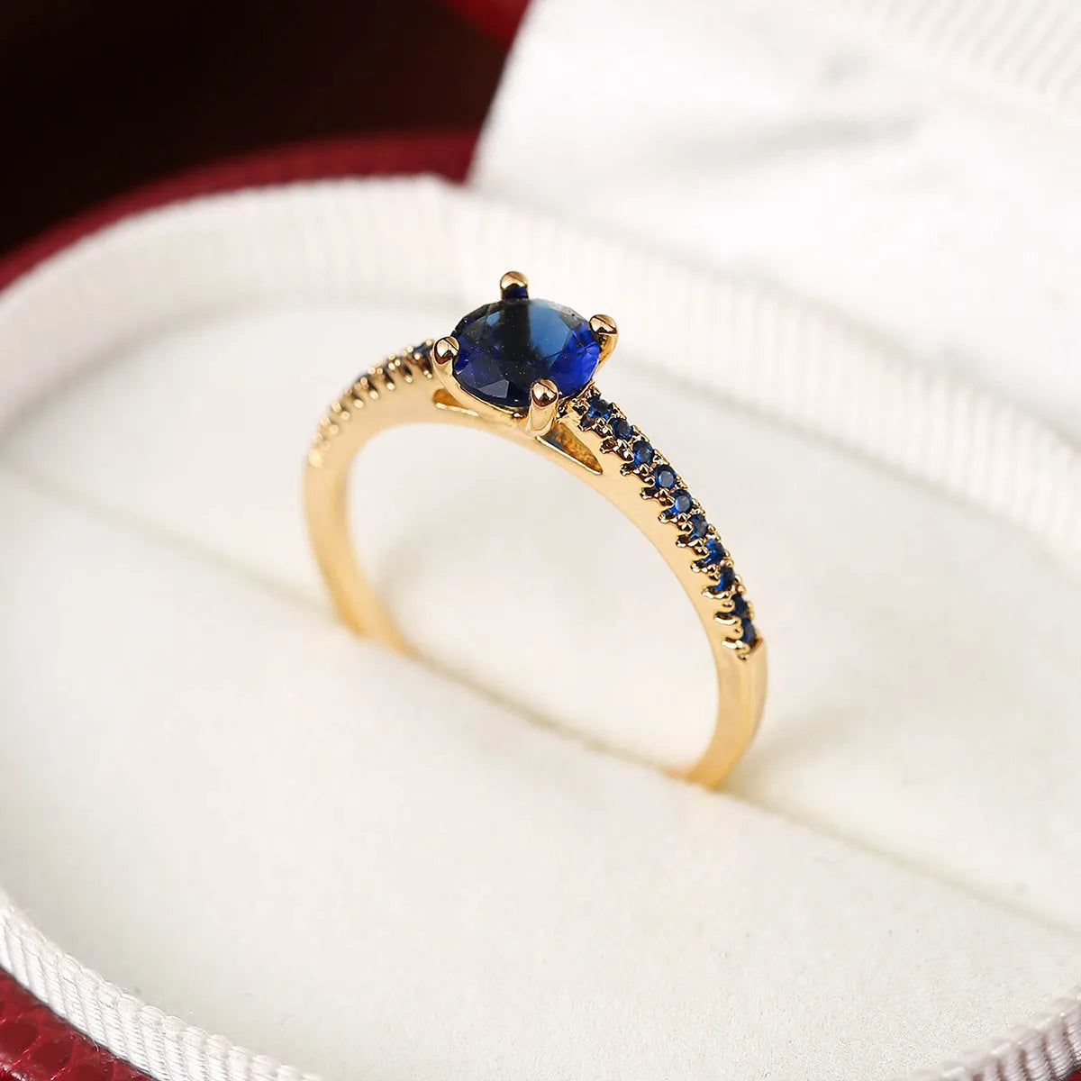 A hexagonal geometric ring with a zircon stone, shown in a gun black and rose red electroplated finish on a finger.