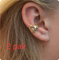 Gold coloured starfish and conch drop earrings on a white background.