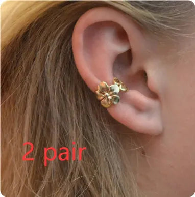 Gold coloured starfish and conch drop earrings on a white background.