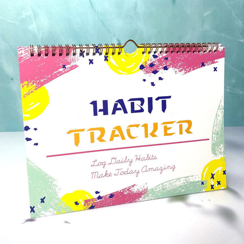 A5 habit tracking notebook open on a desk, showing internal pages, available in four colour options.