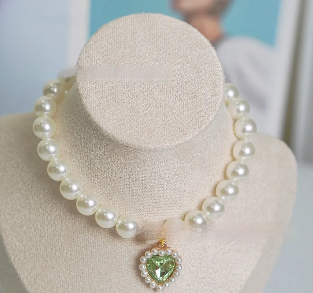Pearl necklace cat collar with heart-shaped gem charm in various colours on a white background.