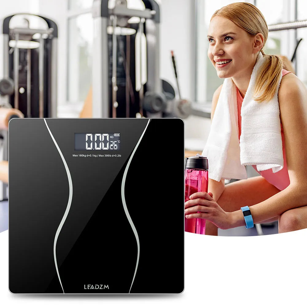 Black electronic digital body scale on a floor, showing a weight reading.
